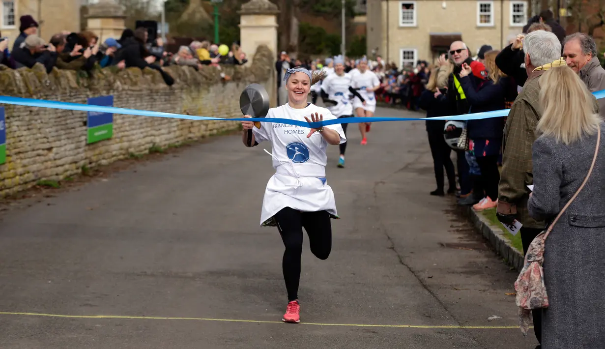 Kaia Larkas mencapai finis dalam lomba lari sembari membawa wajan berisi pancake di Olney, Buckinghamshire, Inggris, Selasa (28/2). Lomba yang digelar pada Hari Pancake atau Pancake Day ini diadakan satu hari menjelang Rabu Abu. (AP Photo/Alastair Grant)