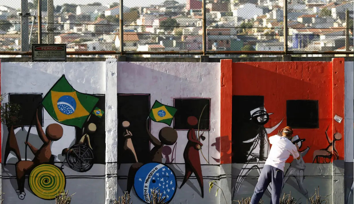 Seorang seniman terlihat sedang membuat lukisan grafiti di salah satu tembok yang ada di Sao Paulo, Brasil, (3/6/2014). (REUTERS/Paulo Whitaker)