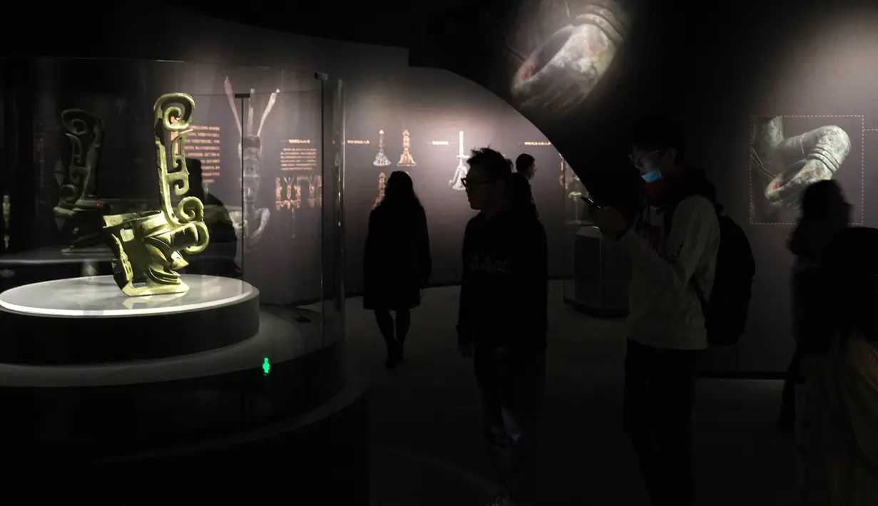 Pengunjung mengamati benda-benda yang dipamerkan dalam sebuah pameran khusus Reruntuhan Sanxingdui prasejarah yang digelar di Museum Universitas Shanghai, Shanghai, China timur, pada 21 November 2020. (Xinhua/Ren Long)