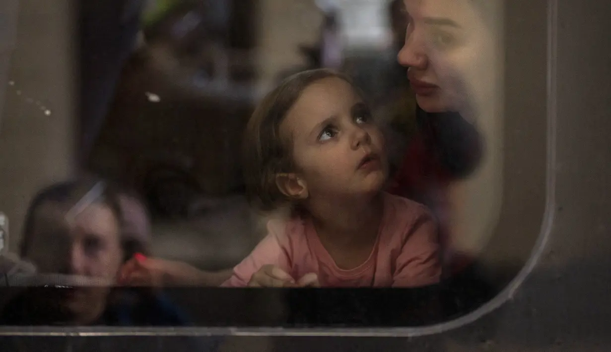 Elina (4) melihat ibunya Lolita dalam kereta menuju Polandia untuk melarikan diri dari perang di stasiun kereta di Lviv, Ukraina, 15 April 2022. Pria Ukraina berusia 18-60 tahun dilarang meninggalkan negaranya dan diminta untuk berperang. (AP Photo/Emilio Morenatti)