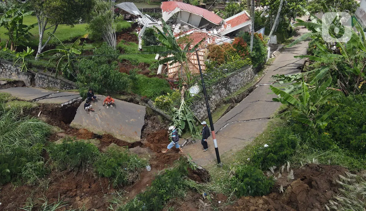 Foto udara memperlihatkan jelanan yang ambles akibat gempa di Desa Sarampad, Kabupaten Cianjur, Jawa Barat, Selasa (22/11/2022). Warga yang terdampak gempa berharap bantuan seperti makanan, obat-obatan, selimut, dan petugas medis bisa segera datang. (Liputan6.com/Herman Zakharia)