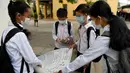 Para siswa mengenakan masker mendiskusikan pekerjaan rumah di sebuah sekolah di Phnom Penh (28/1/2020). Virus corona dapat menyebabkan infeksi pernapasan akut seperti pneumonia seperti infeksi pernapasan akut. (TANG CHHIN SOTHY/AFP)