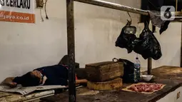 Seorang pria tidur di los daging non halal di Pasar Senen, Jakarta, Senin (13/9/2021). Manajer Umum dan Humas Perumda Pasar Jaya Gatra Vaganza mengatakan pihaknya sudah memanggil dan memberi sanksi administrasi kepada pedagang daging anjing di Pasar Senen Blok III tersebut (Liputan6.com/Johan Tallo)