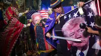 Dukun melakukan ritual mistik dengan memegang gambar Presiden Donald Trump dan pesaingnya dari Demokrat Joe Biden, di Lima, Peru, Rabu (16/9/2020). Para dukun berkumpul untuk memprediksi siapa pemenang dari pemilihan presiden AS yang akan dihelat pada 3 November mendatang. (AP Photo/Rodrigo Abd)
