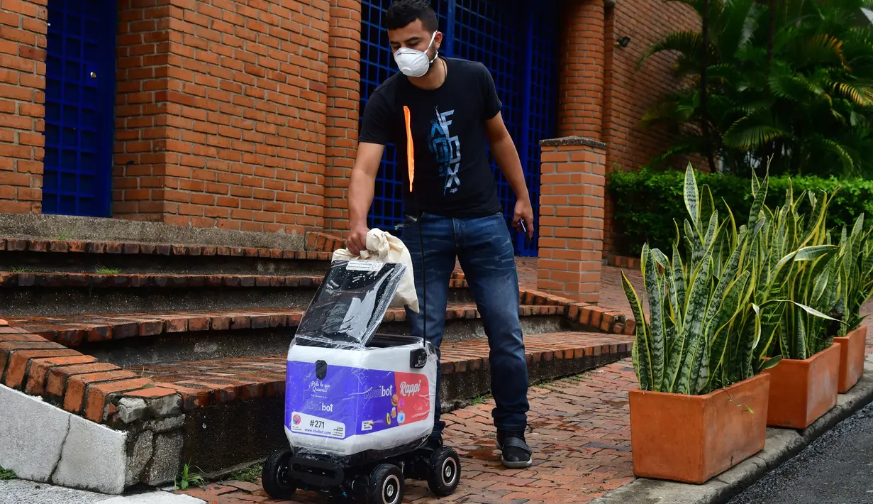 Seorang pelanggan menerima pesanan makanan yang dikirim ke rumahnya oleh robot, di Medellin, Selasa (21/4/2020). Robot yang bergerak dengan empat roda itu digunakan untuk mengangkut Pesanan dari berbagai restoran di Kolombia dengan pembayaran digital. (AP/Luis Benavides)