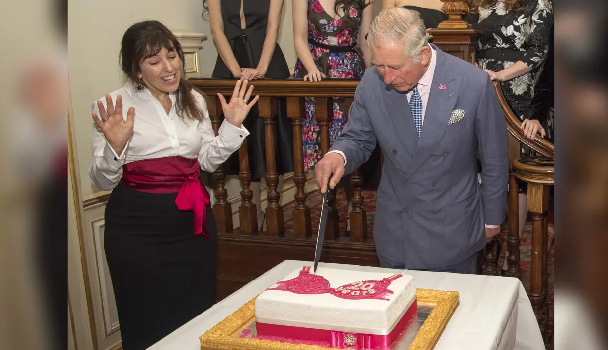 Pangeran Charles bersama pendiri Walk the Walk Nina Barough memotong kue bergambar bra saat menghadiri perayaan ulang tahun ke-20 Walk the Walk di Clarence House, London (23/11). (AFP PHOTO/POOL/Arthur Edwards)