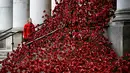 Anna Wigley mendongak ke arah karya seni bunga poppy bertajuk 'Weeping Window' di The Imperial War Museum, London, Kamis (4/10). Karya seni untuk memperingati Perang Dunia I itu akan dipajang hingga 18 November. (AP Photo/Kirsty Wigglesworth)