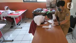 Guru mengawasi siswa saat simulasi Pembelajaran Tatap Muka Terbatas (PTMT) di SDN 03 Cinere, depok, Jawa Barat, Selasa (28/09/2021). Pemkot  Depok hari ini menyelenggarakan simulasi Pembelajaran Tatap Muka Terbatas (PTMT) dari jenjang TK sampai SMP Negeri. (merdeka.com/Arie Basuki)