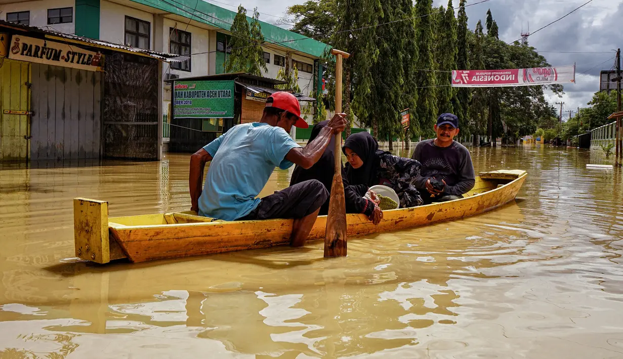 Warga menggunakan perahu untuk melewati jalan yang tergenang banjir setelah hujan lebat dan tanggul jebol, di Lhoksukon, Aceh Utara, 7 Oktober 2022. (AFP/Azwar Ipank)