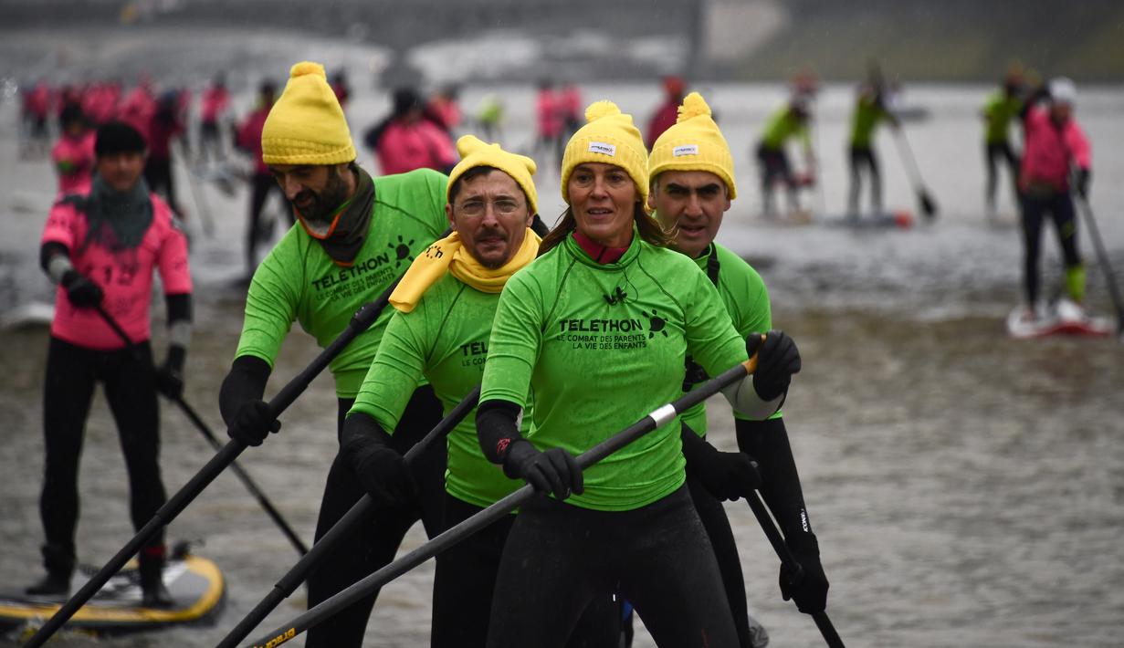 Presenter televisi Prancis Nathalie Simon dan timnya ambil bagian pada perlombaan dayung sambil berdiri Nautic SUP Paris di sungai Seine, Minggu (3/12). Nautic SUP Paris merupakan lomba dayung sambil berdiri terbesar di dunia. (AFP PHOTO/CHRISTOPHE SIMON)