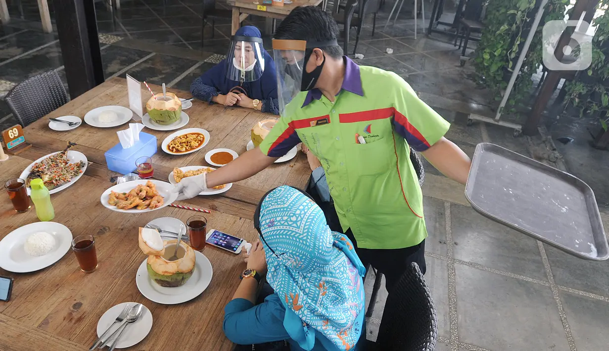 Pelayan mengenakan pelindung wajah saat melayani pengunjung di Restoran Bandar Djakarta, Alam Sutra, Tangerang Selatan, Banten, Rabu (10/6/2020). Tangerang dan Tangerang Selatan menjalankan PSBB transisi menuju kenormalan baru dengan menerapkan protokol kesehatan COVID-19. (merdeka.com/Arie Basuki)