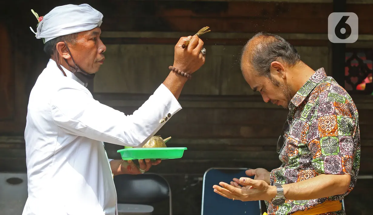 Pemuka agama memercikkan air suci di Pura Aditya Jaya di Jakarta, Selasa (24/3/2020). Ibadah hari suci Nyepi Tahun Baru Saka 1942 di Pura Aditya Jaya tidak menyelenggarakan persembahyangan, namun untuk sembahyang dibatasi dalam mencegah penularan Covid-19. (Liputan6.com/Herman Zakharia)