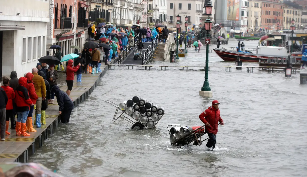 Warga berjalan melewati papan saat gelombang pasang menerjang Venesia, Italia, Selasa (12/11/2019). Venesia dilanda banjir akibat gelombang pasang setinggi 127 cm. (AP Photo/Luca Bruno)