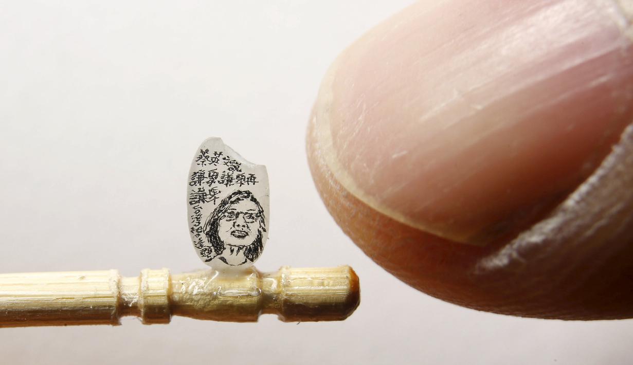 Seniman Taiwan, Chen Forng-Sean berpose dengan karya terbarunya berupa lukisan wajah Presiden Taiwan terpilih, Tsai Ing-wen, yang dilukis di atas sebutir beras, di Taipei, 18 April 2016. (REUTERS/Tyrone Siu)