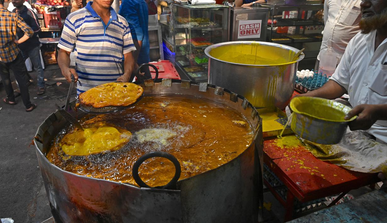 Dalam gambar pada 3 April 2022, juru masak menggoreng Malpua, hidangan manis tradisional India untuk umat Muslim pada hari pertama bulan suci Ramadhan di Mumbai. Masjid dan jalan-jalan pasar penuh dengan keramaian malam, tergoda oleh aroma manisan manis untuk berbuka puasa. (MUKHERJEE/AFP)