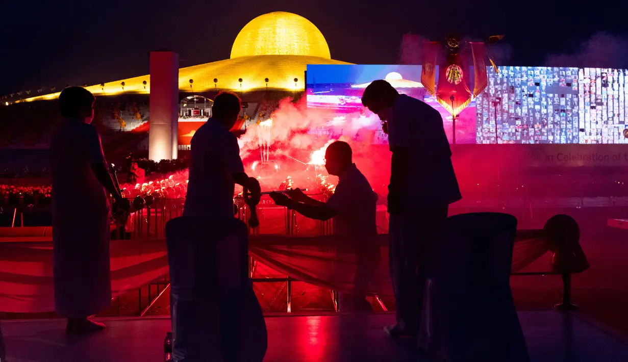Orang-orang menyalakan suar selama perayaan Makha Bucha di kuil Wat Dhammakaya di provinsi Pathum Thani, utara Bangkok (16/2/2022). Makha Bucha merupakan salah satu hari raya terpenting bagi para penganut agama Buddha. (AFP/Jack Taylor)