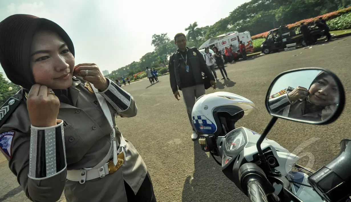 Seorang polwan saat membetulkan jilbabnya sebelum bertugas di pelataran Silang Monas, Jakarta, Jumat (27/3/2015). Polwan di seluruh Indonesia akhirnya diperbolehkan mengenakan jilbab. (Liputan6.com/Faizal Fanani)
