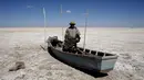 Seorang nelayan dari kelompok etnik Urus berdiri di atas perahunya yang tergeletak di Danau Poopo, La Paz, Bolivia, (17/12). Banyak nelayan kehilangan pekerjaannya akibat keringnya danau ini. (REUTERS/David Mercado)