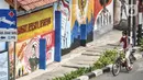 Pengendara sepeda melintas di depan mural bertemakan Pancasila di Kampung Pancasila kawasan Galur, Johar Baru, Jakarta, Selasa (1/6/2021). Kelurahan Galur membuat Kampung Pancasila yang dihiasi mural sebagai bentuk mengingatkan masyarakat akan Pancasila sebagai dasar negara. (merdeka.com/Iqbal S. Nu
