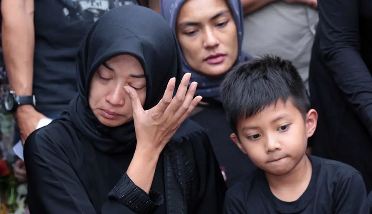 Dengan mengenakan pakaian hitam, serta hijab warna senada, beberapa kali istri Muhammad Fachroni alias Oon mengusap air matanya yang mulai membasahi pipinya. (Deki Prayoga/Bintang.com)