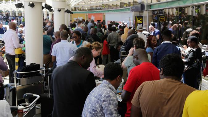 Penumpang yang terdampar setelah penundaan penerbangan karena aksi mogok pekerja maskapai keluar dari bandara JKIA di Nairobi, Rabu (6/3). Para penumpang yang sudah menunggu lama hingga berjam-jam, diminta meninggalkan bandara. (AP Photo/Khalil Senosi)