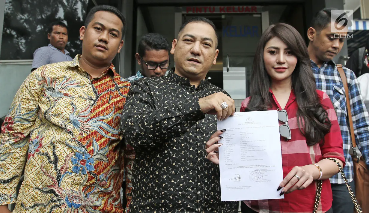 Model seksi Widuri Agesty dan kuasa hukumnya, Krisna Murti menunjukkan tanda bukti lapor di Polda Metro Jaya, Selasa (7/11). Widuri Agesty resmi melaporkan kasus pencatutan foto dirinya di katalog Alexis baru-baru ini. (Liputan6.com/Herman Zakharia)