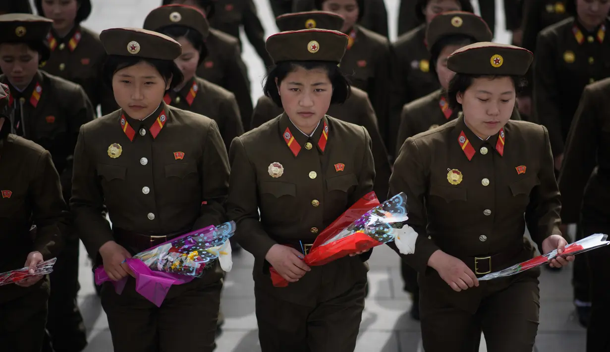 Sejumlah tentara wanita Korea Utara membawa bunga untuk memberi  penghormatan kepada patung-patung Kim Il Sung dan Kim Jong Il di Pyongyang (15/4). Mereka melakukan penghormatan untuk memperingati ulang tahun Kim Il Sung.  (AFP Photo/Ed Jones)