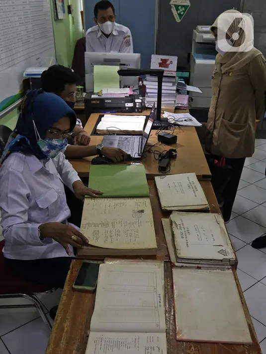 Petugas Dinas Perpustakaan dan Kearsipan (Dispusip) Provinsi DKI Jakarta memeriksa arsip sekolah di SMAN 77, Cempaka Putih, Jakarta Pusat, Rabu (24/11/2021). Digitalisasi sekaligus mendukung target pemerintah bahwa seluruh arsip nasional sudah go digital pada 2024 (Liputan6.com/Herman Zakharia)