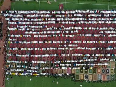 Dalam pandangan udara ini, umat Islam melaksanakan Sholat Idul Fitri , yang menandai berakhirnya bulan suci Ramadhan, di sebuah stadion sepak bola di Kota Kuwait, Jumat (21/4/2023). (Photo by YASSER AL-ZAYYAT / AFP)