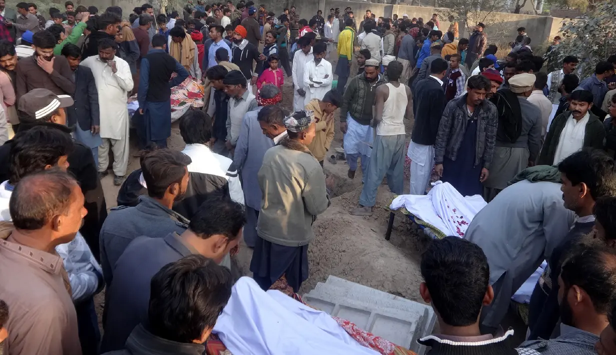 Sejumlah orang berkumpul di pemakaman korban tewas minuman keras oploson di Toba Tek Singh sekitar 338 km dari Islamabad, Selasa (27/12). Selain memakan korban jiwa, minuman oplosan rumahan itu juga membuat puluhan orang dilarikan ke rumah sakit (STR/AFP)