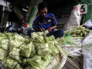 Perajin membuat kulit ketupat dari janur saat berdagang di Pesanggrahan, Jakarta, Kamis (20/4/2023). (Liputan6.com/Johan Tallo)