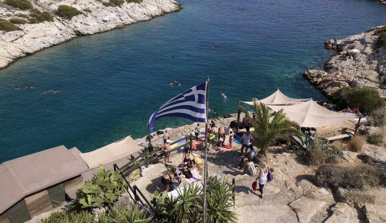 Orang-orang berfoto di sebelah bar pantai di pinggiran Vouliagmeni, barat daya Athena, Yunani, Kamis (29/7/2021). Salah satu gelombang panas paling parah yang tercatat sejak 1980-an melanda Eropa tenggara. (AP Photo/Yorgos Karahalis)