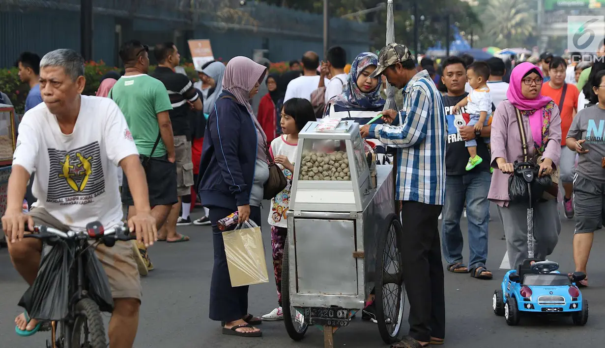 Pengunjung membeli makanan saat pelaksanaan car free day di sepanjang Jalan Sudirman, Jakarta, Minggu (1/7). Kurangnya pengawasan menyebabkan banyak PKL yang berjualan tidak pada tempatnya dan memenuhi area CFD. (Liputan6.com/Immanuel Antonius)