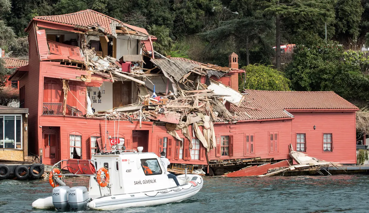 Sebuah perahu penjaga pantai menuju gedung bersejarah yang rusak di pantai Bosphorus, Istanbul, Turki (7/4). Gedung Hekimbasi Salih Efendi itu rusak berat usai ditabrak kapal tanker. (AFP Photo/Gurcan Ozturk)