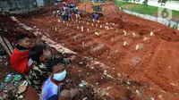 Anak-anak berada di lahan baru Tempat Pemakaman Umum (TPU) khusus COVID-19, Jombang, Tangerang Selatan, Banten,Senin (26/7/2021). Pembukaan lahan baru TPU khusus COVID-19 dikarenakan tingginya angka kematian COVID-19 di wilayah tersebut. (merdeka.com/Arie Basuki)