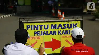 Petugas memasang penunjuk akses masuk pengunjung di Taman Margasatwa Ragunan, Jakarta, Sabtu (20/6/2020). Ragunan mulai dibuka kembali untuk pengunjung pada Sabtu ini di masa PSBB transisi dengan pembatasan dan penerapan protokol kesehatan yang ketat. (Liputan6.com/Herman Zakharia)