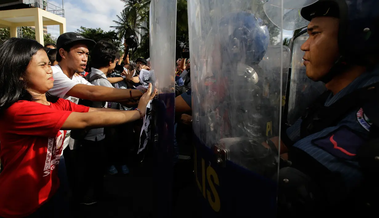 Para pengunjuk rasa saling dorong dengan polisi anti huru-hara saat menggelar aksi di dekat Kedutaan Besar AS di Manila, Filipina (11/11). Bentrokan terjadi akibat massa nekat menerobos masuk ke kantor Kedubes AS. (AP Photo/Aaron Favila)