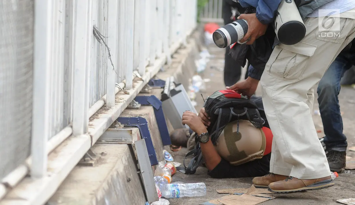 Jurnalis melindungi dirinya dari gas air mata saat meliput demonstrasi mahasiswa yang menolak pengesahan RUU KUHP dan revisi UU KPK di depan Gedung DPR, Jakarta, Selasa (24/9/2019).  Selain mahasiswa, jurnalis terkena imbas gas air mata yang ditembakkan aparat kepolisian. (merdeka.com/Arie Basuki)