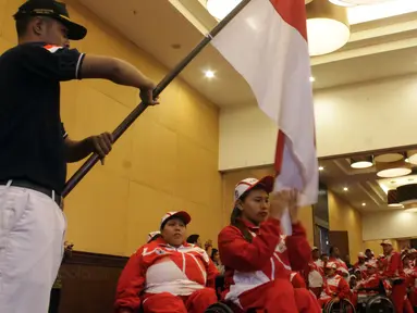 Atlet angkat berat Indonesia, Ni Nengah Widiasih mencium bendera Merah Putih saat pelepasan kontingen Indonesia ke ASEAN Paragames  2017 di Hotel Lorin Solo, Selasa (12/9/2017). Indonesia diharapkan meraih juara umum di APG. (Bola.com/Ronald Seger)