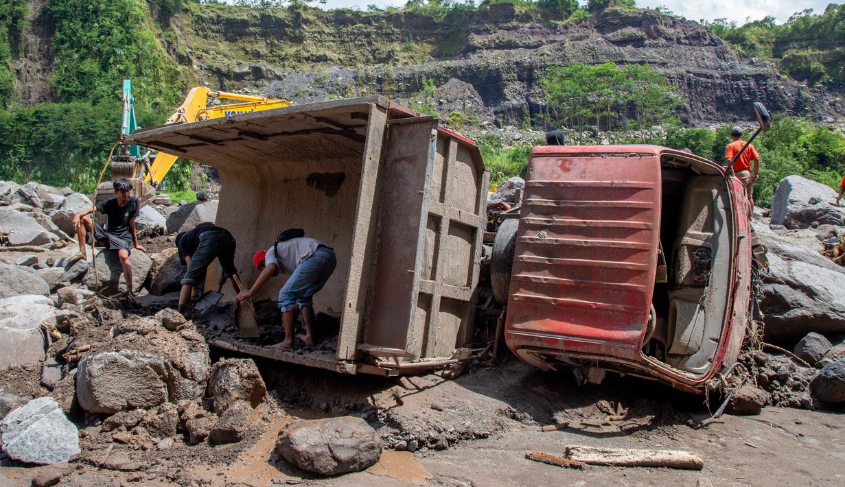 Satu korban ditemukan meninggal dunia di lokasi kejadian pada Selasa (3/3/2026), sementara dua lainnya ditemukan tim SAR gabungan di antara bebatuan di aliran Sungai Senowo, wilayah Dukun, Kabupaten Magelang, Jawa Tengah, pada Rabu (4/3/2026). Tampak dalam foto, warga berusaha mengambil bagian-bagian truk yang terkubur di pasir setelah longsor lumpur akibat hujan dari Gunung Merapi di Sungai Senowo, Magelang, Jawa Tengah pada Rabu 4 Maret 2026. (Devi Rahman/AFP)