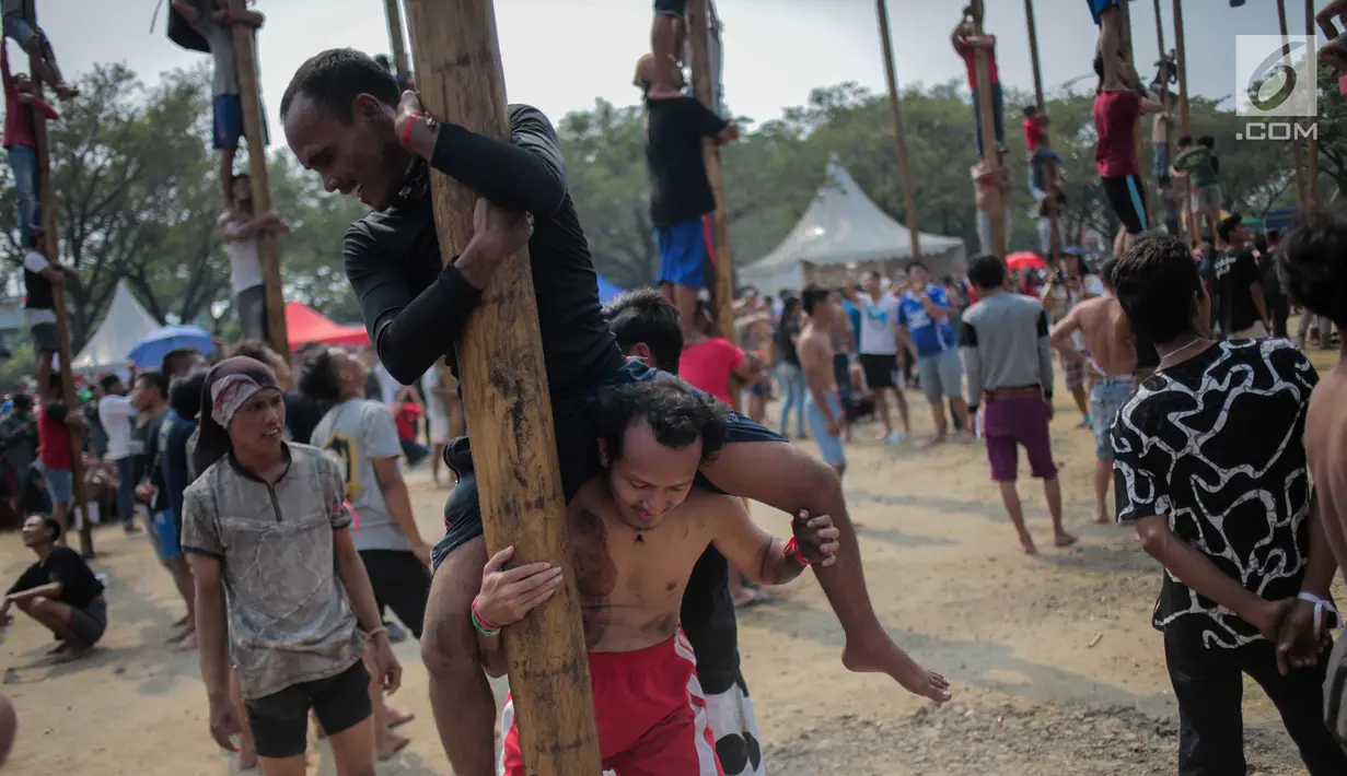 Warga mengikuti lomba Panjat Pinang Kolosal dalam rangka merayakan HUT ke-74 Kemerdekaan RI di Pantai Karnaval Ancol, Jakarta, Senin (17/8/2019). Sebanyak 174 batang pinang dengan beragam hadiah disediakan dalam lomba yang diikuti ratusan warga itu. (Liputan6.com/Faizal Fanani)