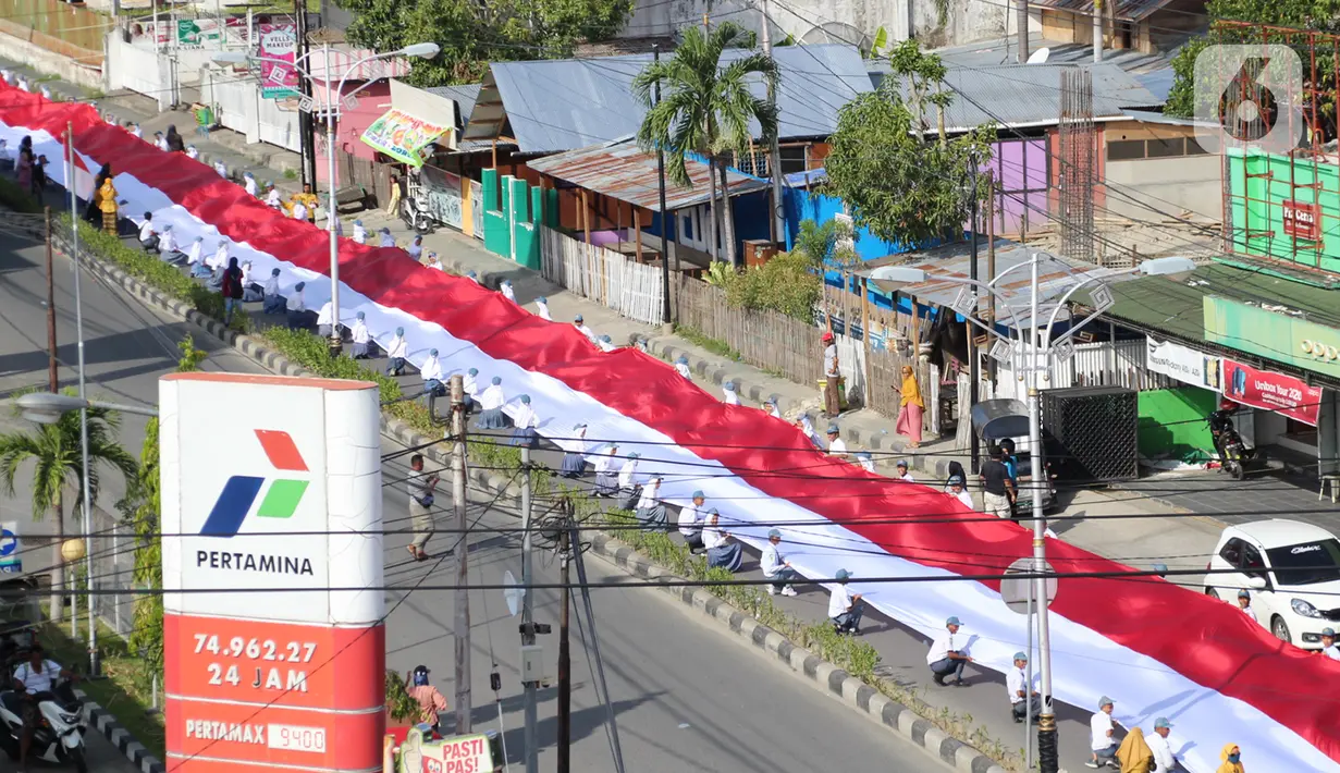 Pelajar SMA membentangkan bendera Merah Putih sepanjang 2,3 kilometer di Jalan Panjaitan dan Jalan Nani Wartabone, Gorontalo, Kamis (23/1/2020). Pembentangan bendera tersebut akan tercatat dalam Museum Rekor Indonesia (MURI). (Liputan6.com/Arfandi Ibrahim)