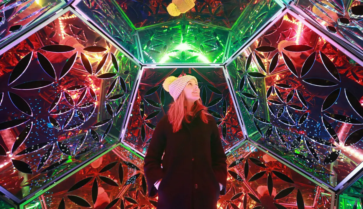 Seorang wanita Martine Basson menikmati seni instalasi lampu karya Amberlights saat festival Canary Wharf Winter Lights di London (16/1). Seni instalasi cahaya karya seniman Amberlights ini berjudul Dazzling Dodecahedron. (Matt Alexander / PA via AP)