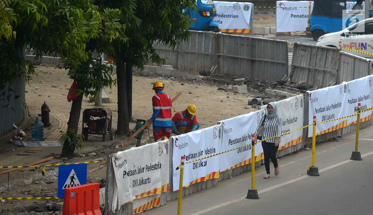 Warga berjalan di samping proyek pelebaran jalur khusus pejalan kaki atau pedestrian di kawasan Sarinah, Jakarta, Rabu (4/7). Pelebaran ini dilakukan untuk menyambut Asian Games 2018. (Merdeka.com/Imam Buhori)