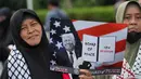 Sebelumnya, Indonesia menyatakan akan bergabung dalam Board of Peace (BOP), sebuah dewan perdamaian yang diinisiasi oleh Amerika Serikat. Pihak Kementerian Luar Negeri menegaskan bahwa keterlibatan Indonesia bertujuan membuka jalur logistik bantuan ke Gaza dan mendorong kemerdekaan Palestina dari dalam forum internasional. Tampak dalam foto, seorang aktivis Muslim memegang poster bergambar Presiden Donald Trump saat unjuk rasa mendukung warga Palestina di Gaza, di depan Kedutaan Besar Amerika Serikat, Jakarta, Jumat 13 Februari 2026. (AP Photo/Achmad Ibrahim)