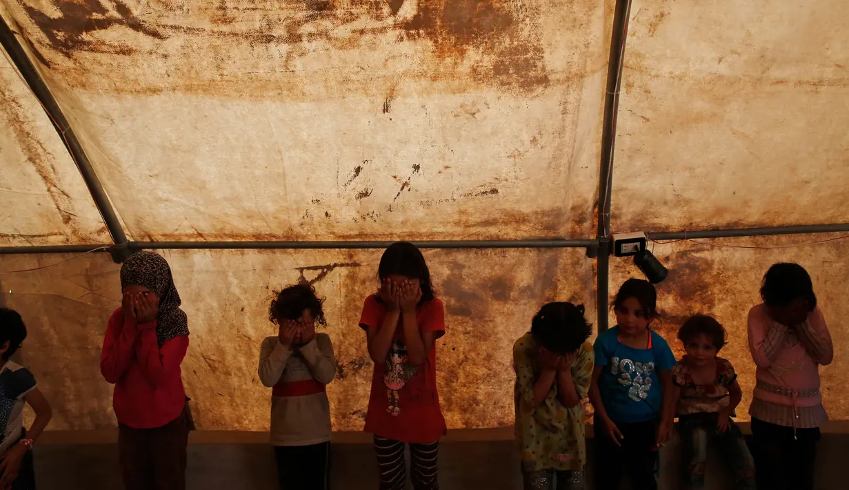 Anak-anak menutupi wajah mereka dalam kegiatan rekreasi di kamp pengungsian al-Bab, Suriah, Selasa (29/5). Anak-anak ini mengikuti berbagai kegiatan, termasuk sekolah darurat, yang digelar oleh para relawan. (AP Photo/Lefteris Pitarakis)