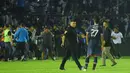 Pemain, ofisial, dan perangkat pertandingan laga Arema Vs Persebaya diberikan kawalan ketat untuk masuk ke dalam ruang stadion karena mereka tak henti-hentinya dilempari botol dan benda-benda lainnya dari tribun Stadion Kanjuruhan, Malang, pada Sabtu (1/10/2022) malam. (Bola.com/Iwan Setiawan)