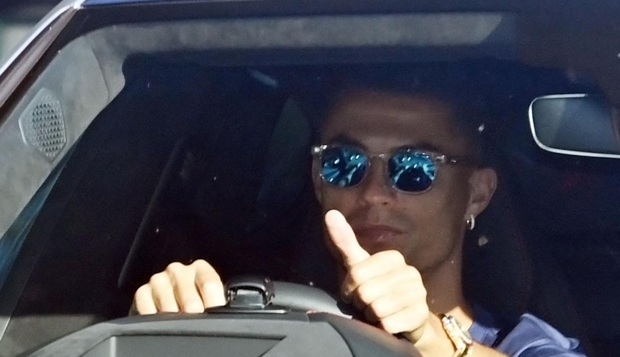 Berada di balik kemudi Lamborghini Urus, Ronaldo yang menggunakan kaca mata tertangkap kamera mengangkat jempolnya saat melewati fans dan para awak media. (Foto: AFP/Paul Ellis)