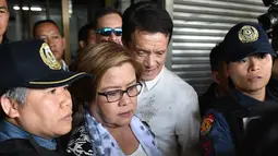 Senator Filipina, Leila de Lima, dikawal aparat keamanan dan didampingi pengacara saat penangkapannya di kota Pasay, selatan Manila, Jumat (24/2). Leila de Lima dituding menerima uang dari para pengedar narkoba di penjara-penjara Filipina (TED ALJIBE/AFP)