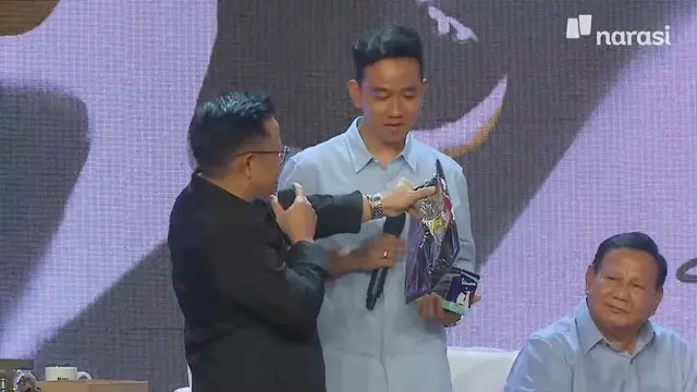 Calon wakil presiden (cawapres) nomor urut satu Muhaimin Iskandar memberikan sebuah kaus kepada cawapres nomor urut tiga Gibran Rakabuming Raka di perayaan 13 tahun Mata Najwa di Taman Ismail Marzuki (TIM), Jakarta Pusat, Minggu (19/11/2023).